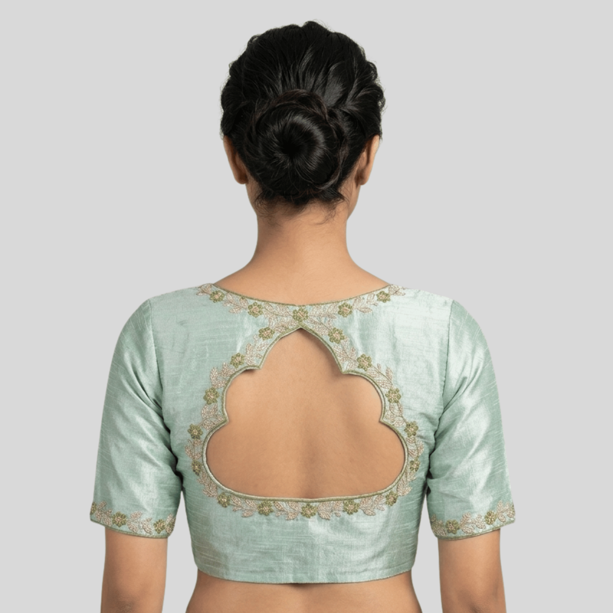 Light green blouse with floral embroidery on a plain background