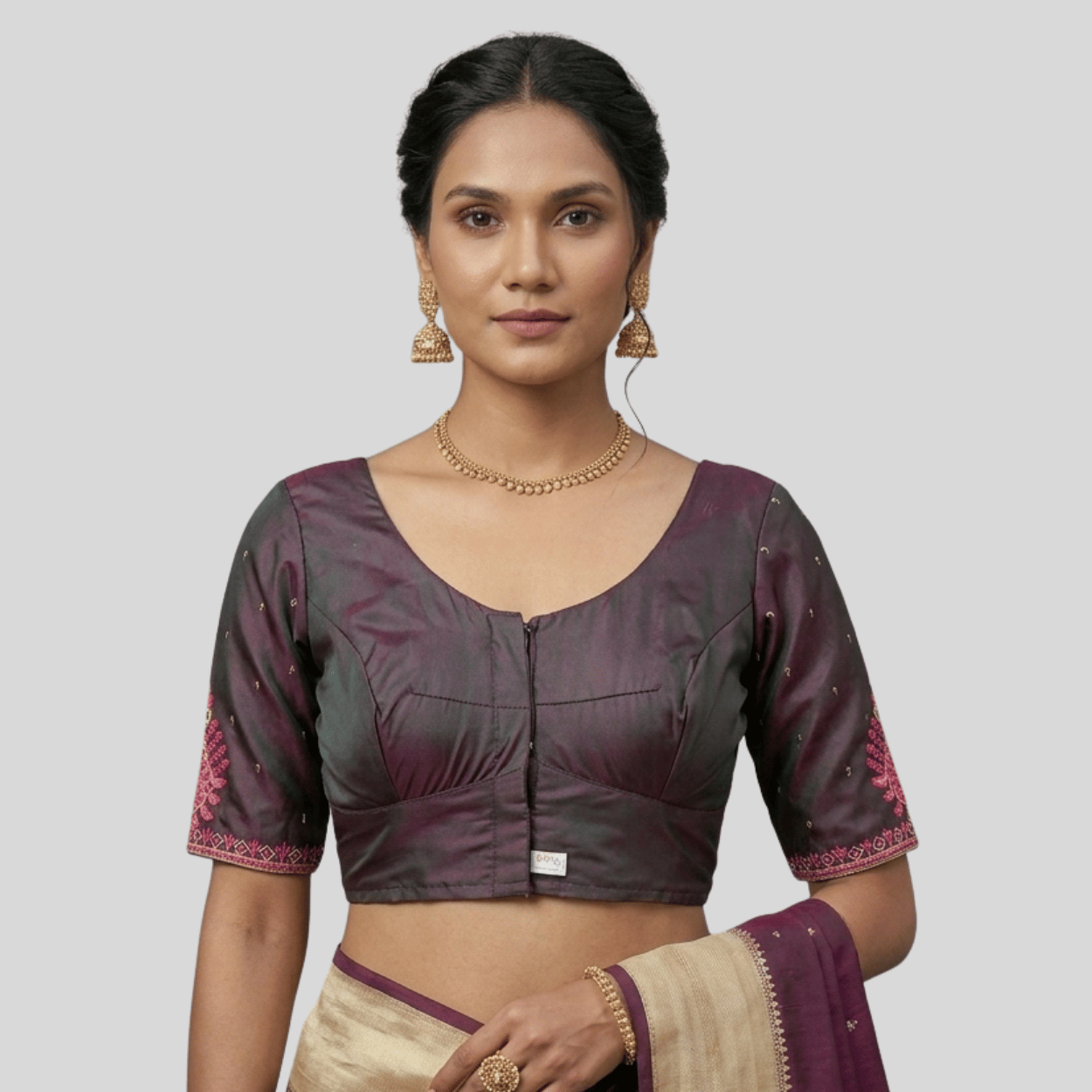 Woman wearing a traditional blouse with floral patterns on a plain background