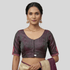 Woman wearing a traditional blouse with floral patterns on a plain background