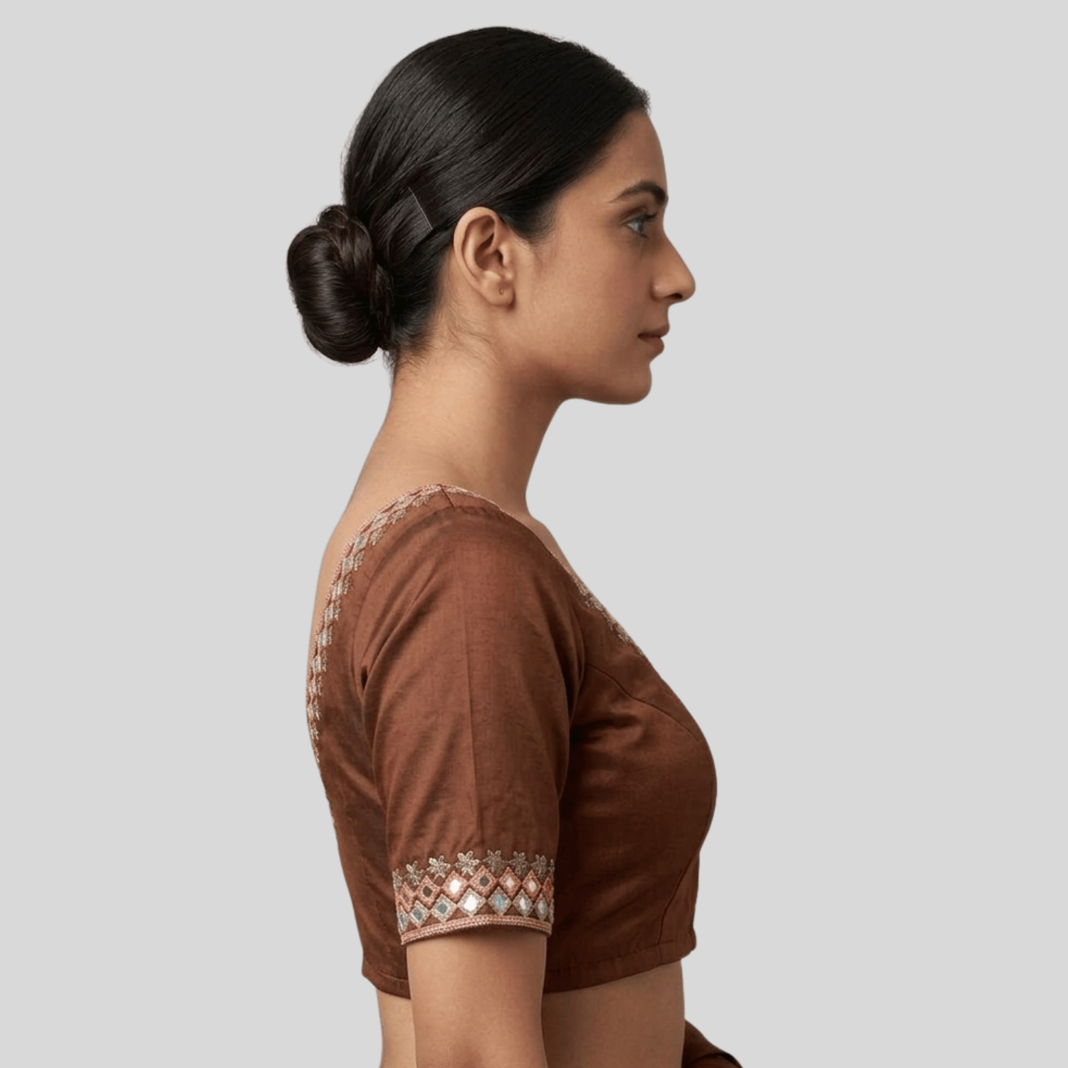 Woman wearing a Mirror work embroidered brown blouse with intricate detailing on a light gray background